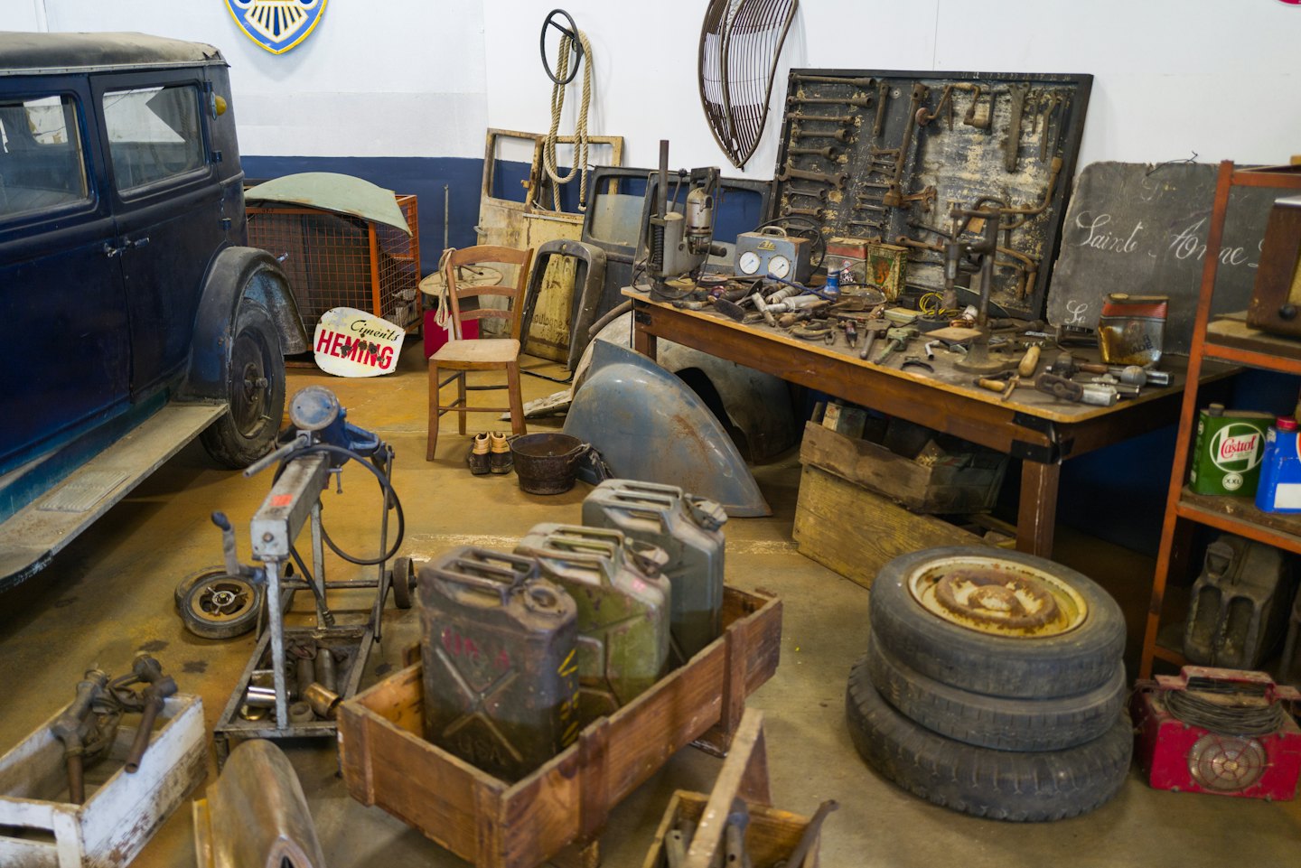Klassischer Oldtimer in einer vollgestopften Oldtimer-Werkstatt.